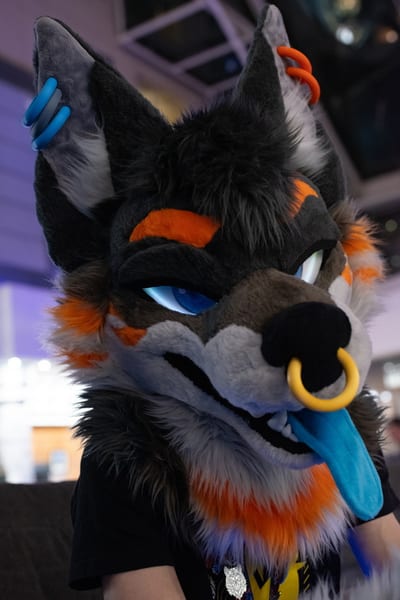 Ethyos looking sleepy at a convention, half-closed blue eyes and tongue out